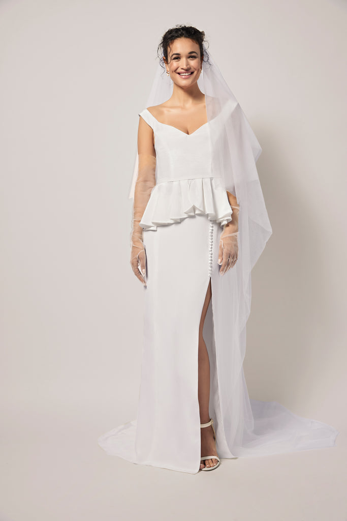 woman wearing off-white straight long skirt in a heavy silk crepe with a front side slit and peplum top with veil